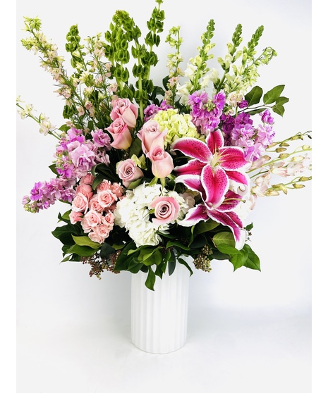 This beautiful design in shades of pink features our leaf wrapped signature clear vase. Lilies, roses, and hydrangea are among other floral textures and elegant greenery 