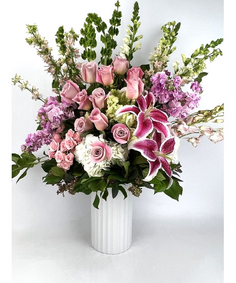 This beautiful design in shades of pink features our leaf wrapped signature clear vase. Lilies, roses, and hydrangea are among other floral textures and elegant greenery 