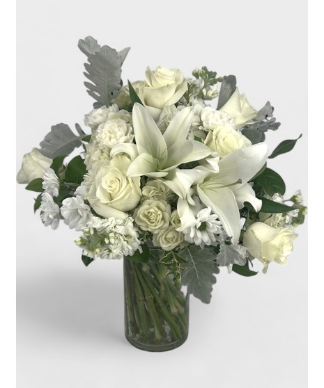 A beautiful mix of roses, lilies, and hydrangea with delicate filler flowers, designed in a clear cube vase.