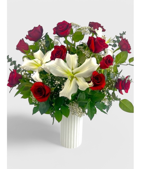 A dozen roses are complimented by the beauty and sweet scent of fragrant white lilies. 