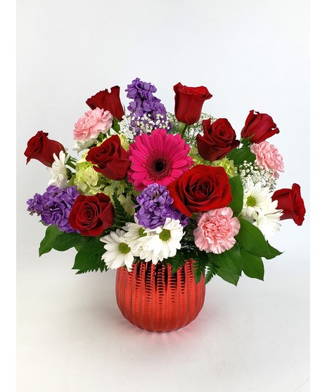 Beautiful mix of  red roses, mums, mini carnations and assorted fillers in a red glass cube.