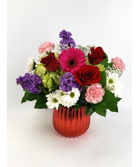 Beautiful mix of  red roses, mums, mini carnations and assorted fillers in a red glass cube.